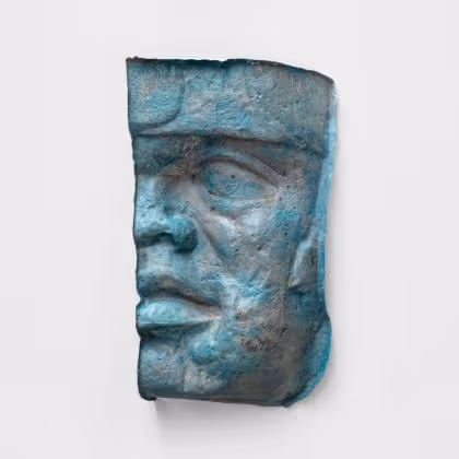 Blue-green weathered sculpture fragment of a human face profile